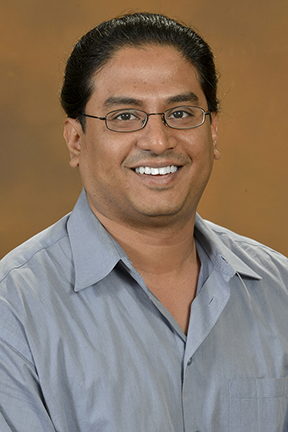 A man wearing glasses smiling for a photo