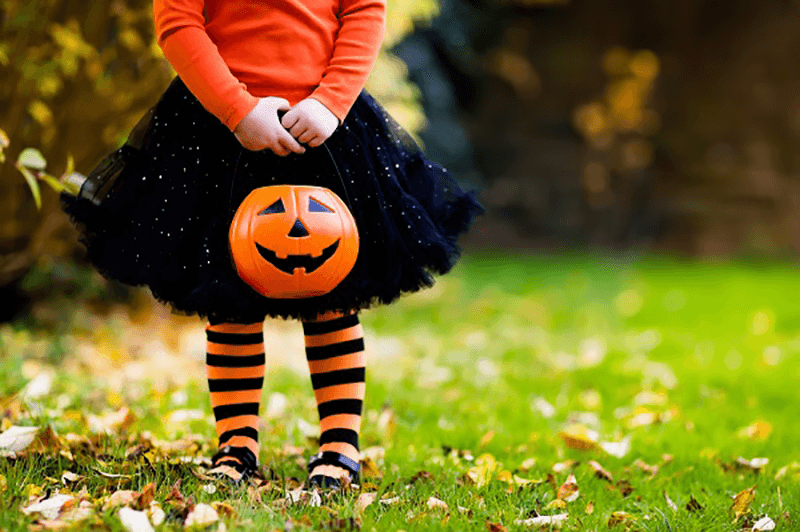 Girl in holding a pumpkin bucket.