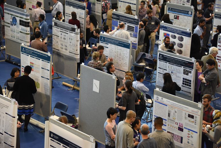 people looking at posters in an auditorium