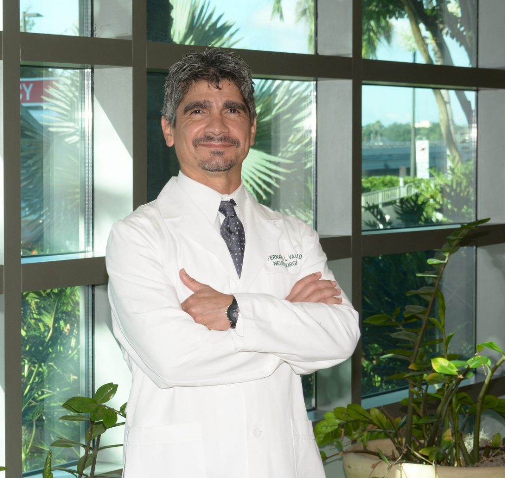 A neuroscientist in lab coat smiles at the camera.