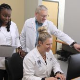 three people looking at a computer