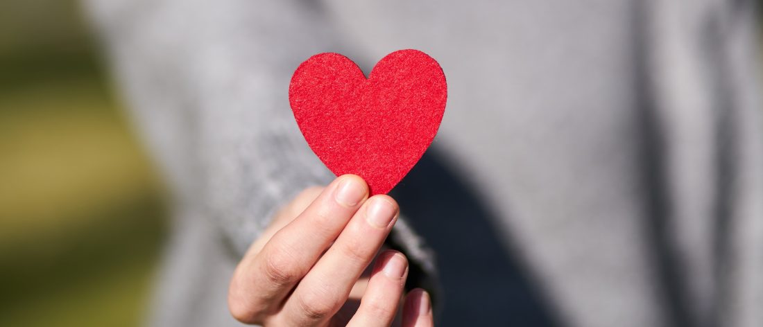 hands holding a paper cutout of a heart