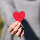 hands holding a paper cutout of a heart