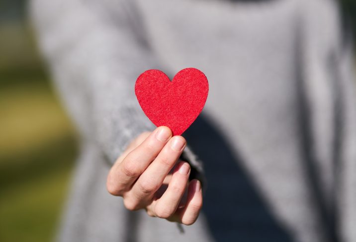 hands holding a paper cutout of a heart