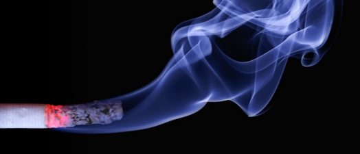 A cigarette with smoke coming off of it.