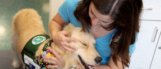 woman petting therapy dog while they smile