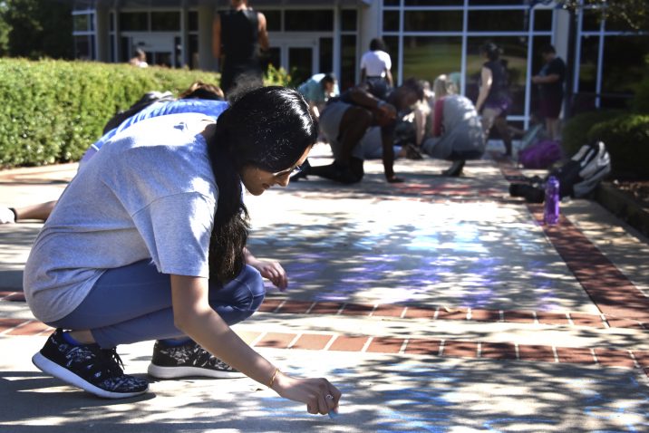 A group of students chalking lines in the sidewalk.