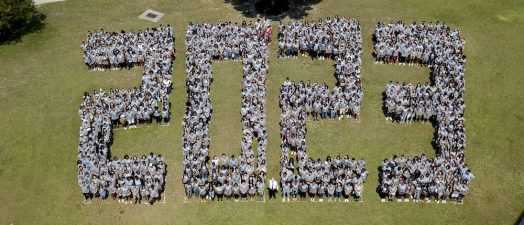 Students standing on a field in the shape of 2023