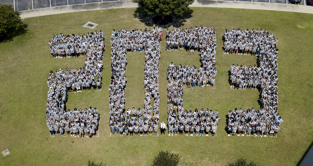 Students standing on a field in the shape of 2023