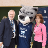 Two people standing with a mascot.