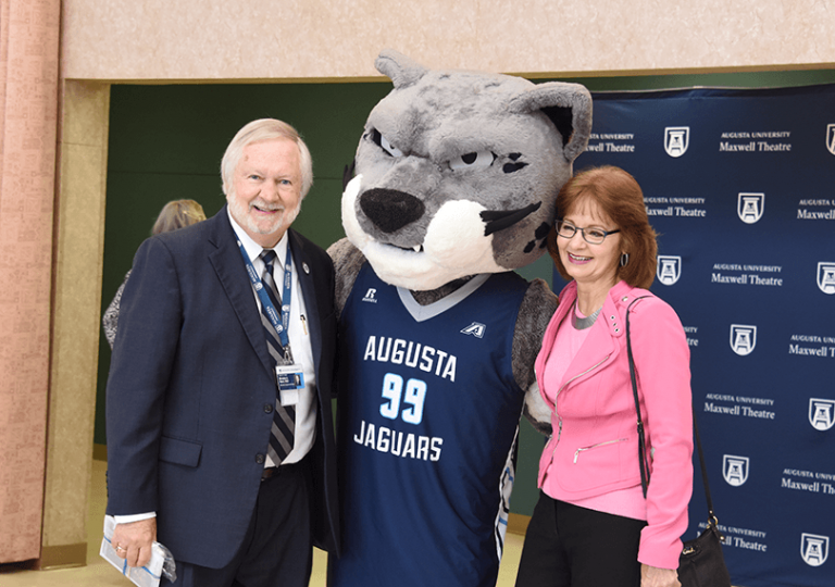 Two people standing with a mascot.