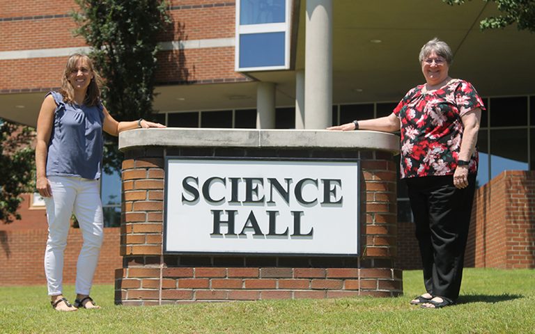Two women standing near a sign