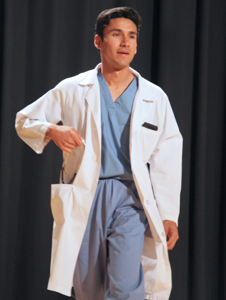 Man on stage with white coat.