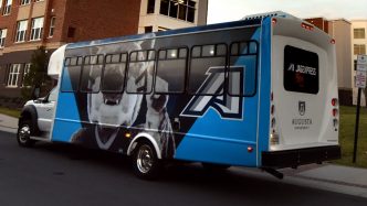 Color photo of Augusta University shuttle with mascot Augustus and the athletic A