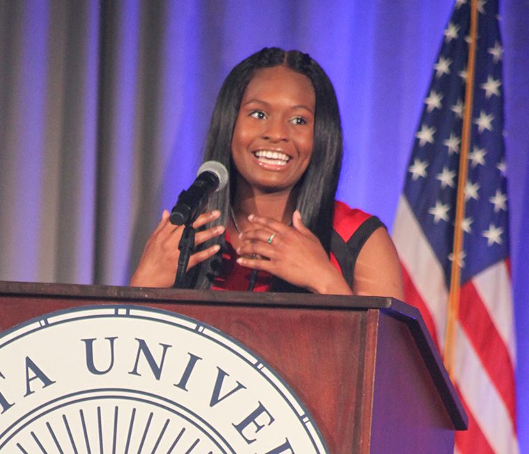 Woman on stage speaking.