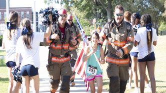 Two firefighters running with a flag.