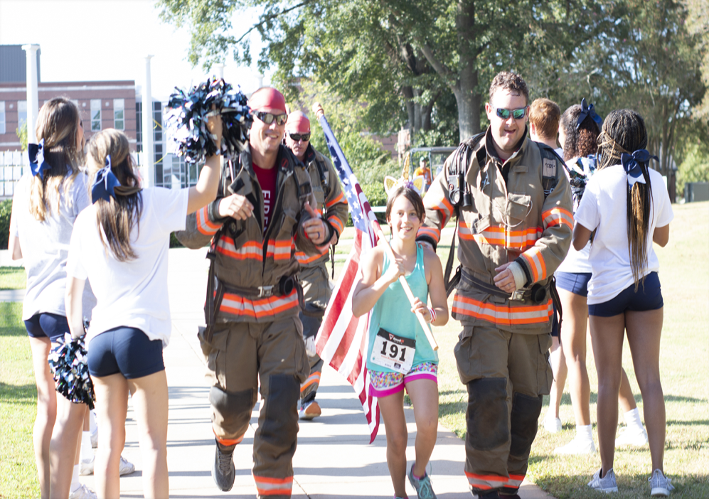 Two firefighters running with a flag.