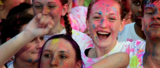 A group of girls smiling with paint on their faces.