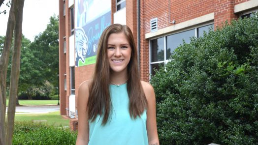 Student standing in front of building.