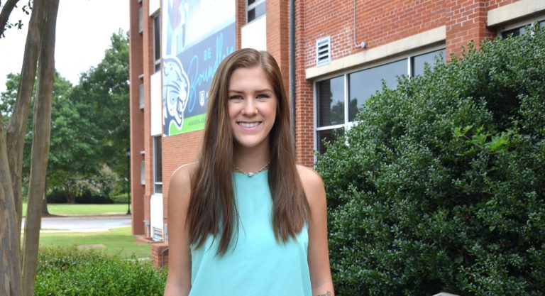 Student standing in front of building.