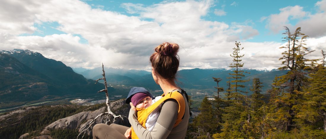 woman holding baby on top of mountain