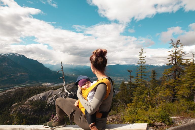 woman holding baby on top of mountain