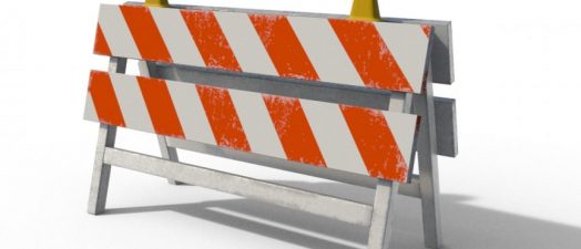 color photo of construction barricades with orange and white stripes and two yellow lights on top