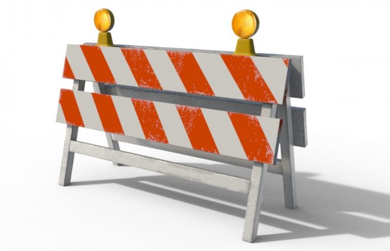 color photo of construction barricades with orange and white stripes and two yellow lights on top