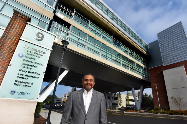 a doctor standing in front of the Georgia Cancer Center building.