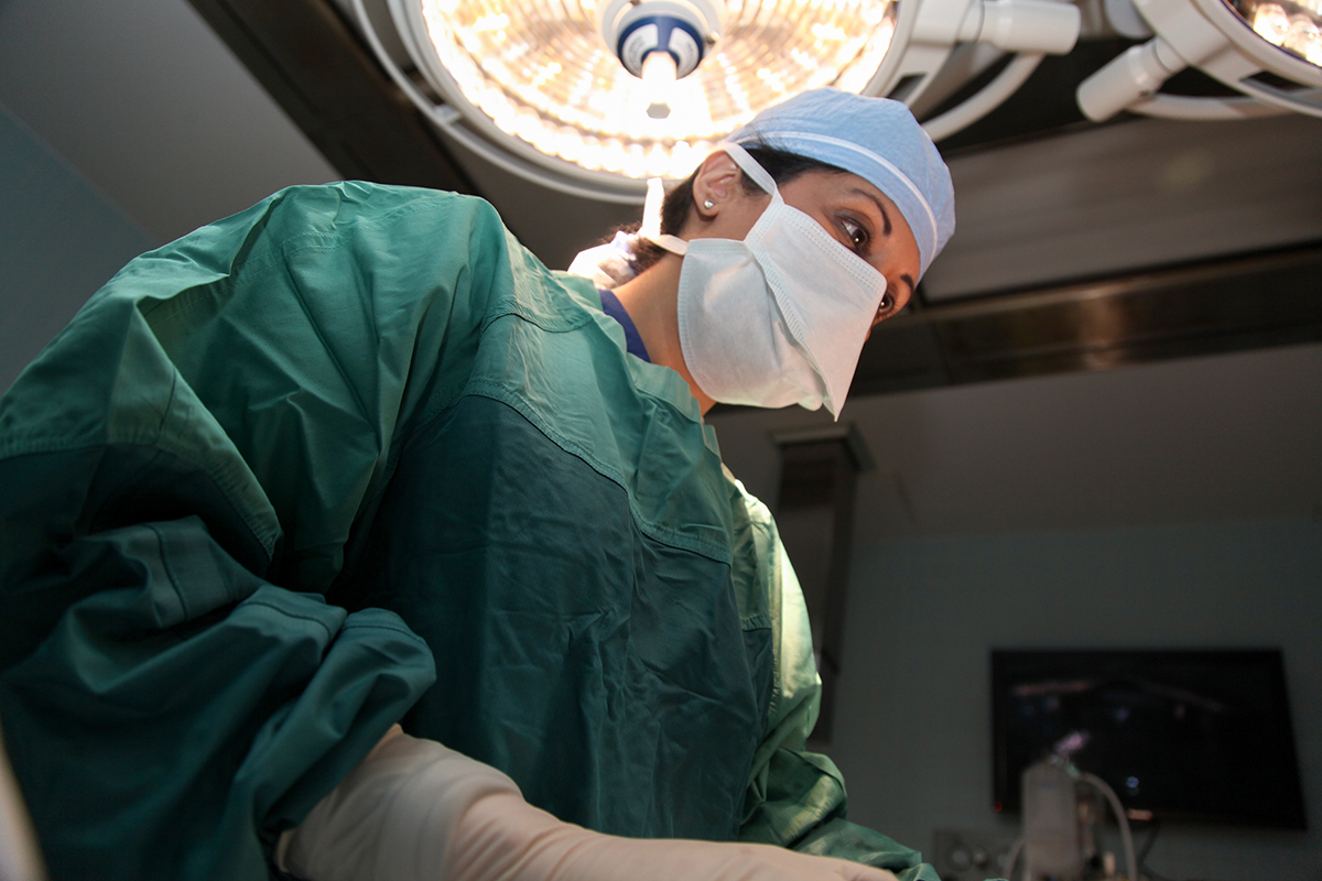 Female surgical oncologist standing over a patient on the operating table