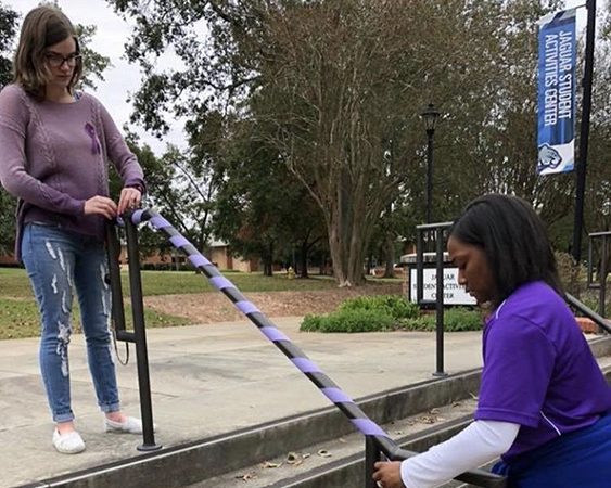 two women putting a ribbon on a stair rail