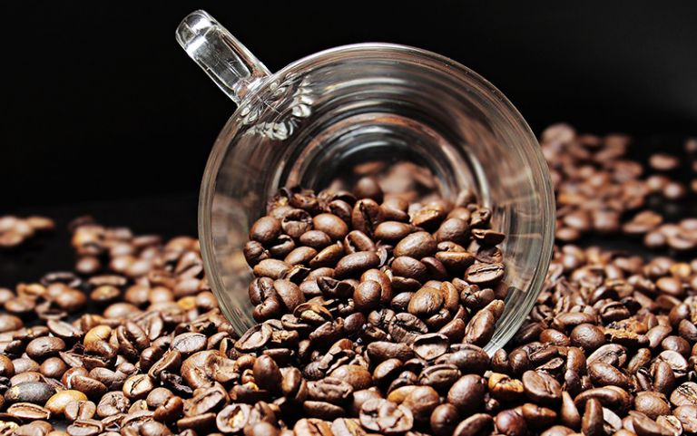 A cup surrounded by coffee beans.