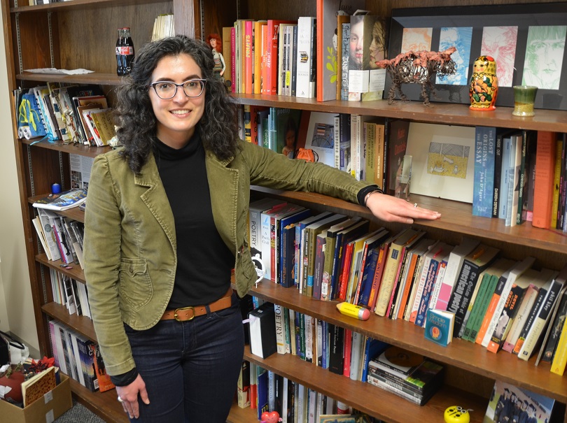 A woman standing by books.