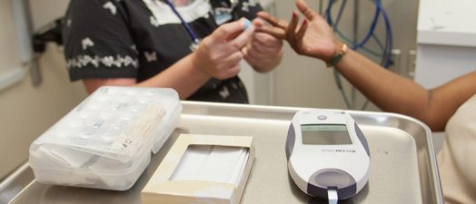 Nurse checking patients blood sugar.
