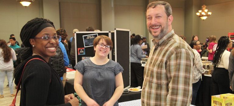 students smiling in front of posters