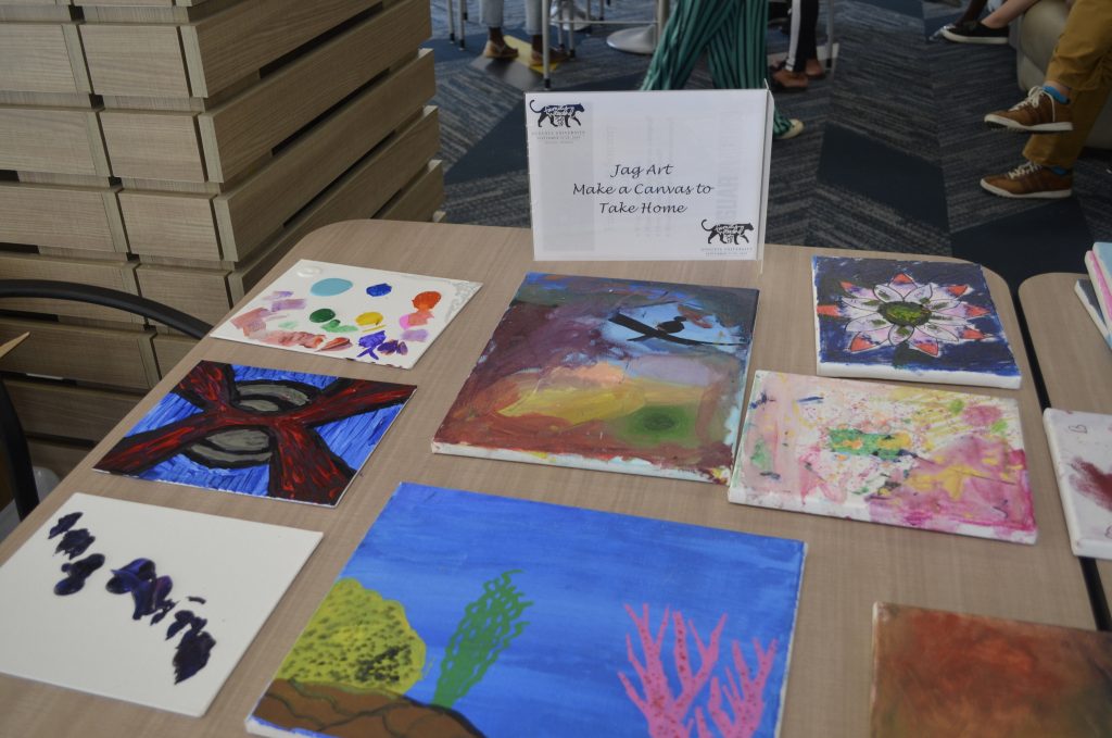 Nine painted canvases sitting out to try on a table. 