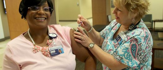 Nurse giving woman a flu shot.