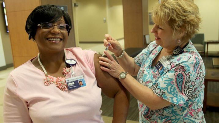 Nurse giving woman a flu shot.