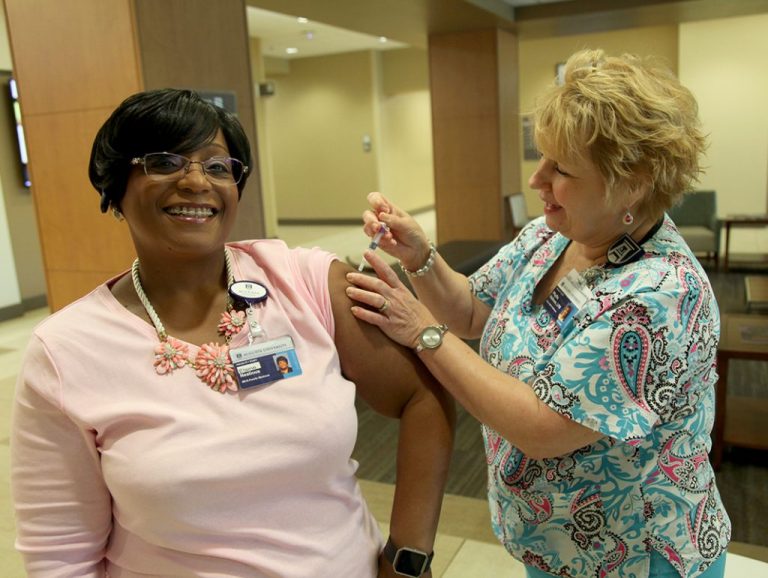 Nurse giving woman a flu shot.