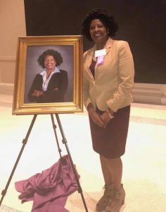 A woman standing next to her picture.