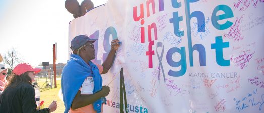 People signing a sign to let others know why they took part in the walk.