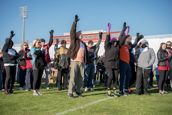 A photo of people taking part in an exercise warm-up before the walk begins.