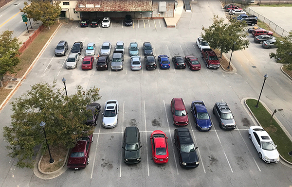 aerial view of paved parking lot and about 30 cars
