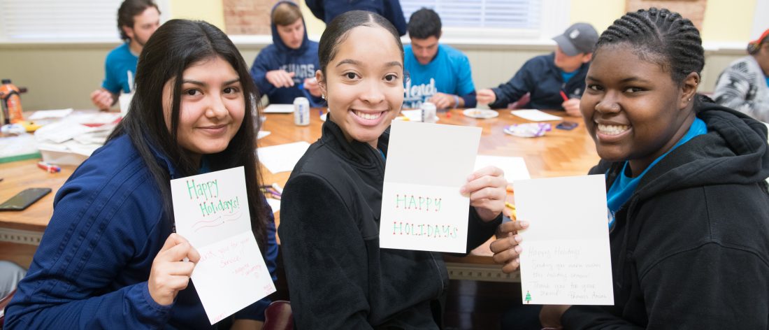 students smiling with handmade holiday cards
