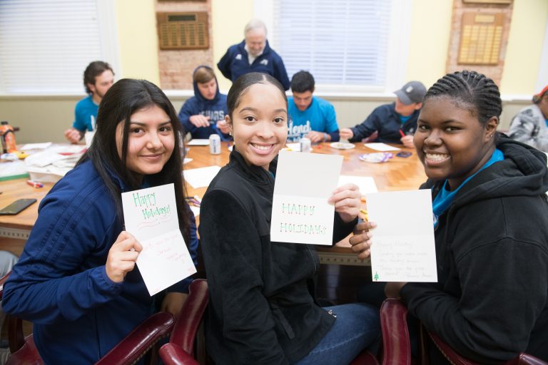 students smiling with handmade holiday cards