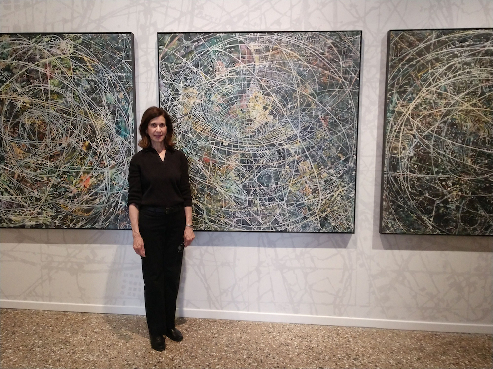 Woman standing in front of her paintings.