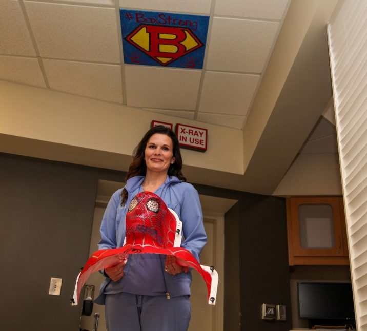 Woman holding a Spider-man mask used for radiation treatment