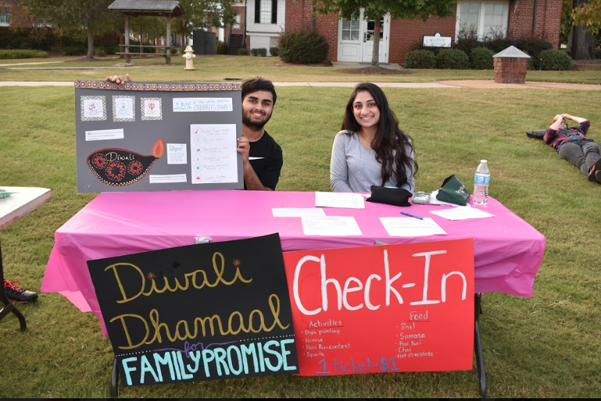 2 students sit at check-in table at Diwali event