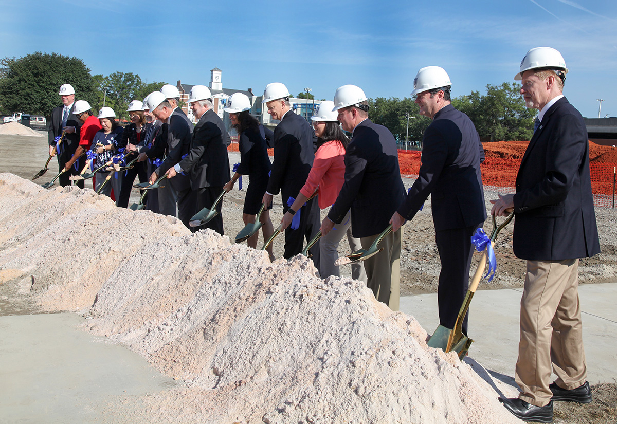 people with shovels standing in front of a dirt pile