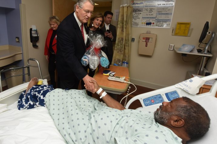 man greeting patient in hospital bed